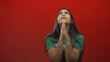 © Krakenimages.com - Woman volunteer wearing green t shirt presses hands together in prayer, eyes upturned and tearful in a red studio; desperation plea.