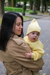 © phpetrunina14 - Mother Holding Baby in Yellow Outfit at Park early autumn