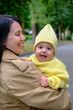 © phpetrunina14 - Mother Holding Baby in Yellow Outfit at Park early autumn