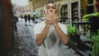 © Krakenimages.com - Man in white t shirt blows kiss with hand to lips on cobbled street, facing camera; affection warmth connection.