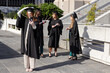 © wavebreak3 - Female classmates wearing gowns and caps, taking selfie with smartphone on terrace holding diplomas