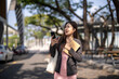 © Wasana - Asian businesswoman smiling holding smartphone notebook walking outdoors