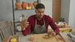 © Krakenimages.com - Man with beard sculpts clay using metal tool while holding smartphone, wearing apron at a pottery studio workspace with tools and pots; focused creativity.