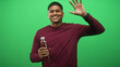 © Krakenimages.com - Man holding pomegranate juice bottle in right hand while smiling and waving at camera in studio; happy wellness refreshment energy.
