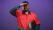 © Krakenimages.com - Man with beard shielding eyes with hand while holding a black toolbox and wearing a red work uniform and reflective strip in studio; determination.