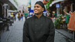 © Krakenimages.com - Man in chef uniform with smiling face looks to side on a cobblestone street outside a cafe; pride hospitality.