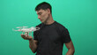 © Krakenimages.com - Hispanic man holds white drone model in open palm in studio under bright green screen; innovation curiosity.