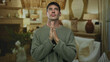 © Krakenimages.com - Young hispanic man with eyes closed and hands pressed together prayer gesture in building living room; serenity.