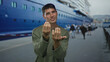 © Krakenimages.com - Man in olive sweater gestures beckoning with bare palms by cruise ship on a port street; invitation longing.