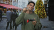 © Krakenimages.com - Man holding red and black game controller points finger at camera in busy street; playful enthusiasm.