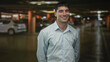 © Krakenimages.com - Man in a light blue shirt shows smiling face amid parked cars in an indoor parking garage; optimism.