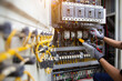 © Eakrin - Electrical service technician use electricity measuring tools equipment checking electric current circuit breaker terminal panel and cable wiring main power distribution board for maintenance system.
