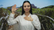 © Krakenimages.com - Hispanic woman in a park making a pledge gesture with greenery in the background, symbolizing promise and commitment in an outdoor setting.