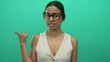 © Krakenimages.com - Young hispanic woman with glasses pointing over her shoulder against an isolated green background, expressing confusion.