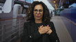 © Krakenimages.com - Middle-aged hispanic woman standing on a boat deck with a sea view, hands over heart, expressing gratitude outdoors, wearing glasses and black jacket, relaxed and serene atmosphere.