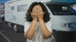 © Krakenimages.com - Middle-aged hispanic woman smiling outdoors in front of a camper van, enjoying a sunny day on the street.