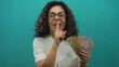© Krakenimages.com - Woman holding mexican pesos making hush gesture on green background with isolated setting.
