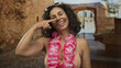 © Krakenimages.com - Middle age hispanic woman points finger to nose gesture on street in old town wearing hawaiian lei and bikini top; playful fun vacation mood.