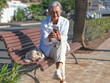 © luciano - Elderly woman sitting on a bench in urban environment typing message on mobile phone reflecting independence and positivity