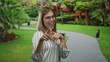 © Krakenimages.com - Woman wearing glasses and striped blouse pointing finger to camera on green lawn in park; playfulness.