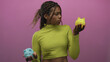 © Krakenimages.com - Woman holding blue and yellow piggy banks in pink studio wearing green turtleneck while comparing choices; financial uncertainty.
