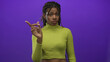 © Krakenimages.com - Woman points finger in purple studio while wearing lime cropped top and showing midriff; disapproval dismissal.