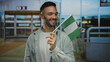 © Krakenimages.com - Young man smiling and waving nigerian flag at airport terminal captures a vibrant multicultural travel experience.