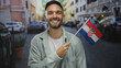 © Krakenimages.com - Young man holding croatian flag smiling on an urban street in a city environment outdoors showcasing national pride and a cheerful demeanor.