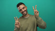 © Krakenimages.com - Young man smiling in front of blue background making peace signs with both hands in a laid-back casual setting showing joyful expression