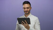 © Krakenimages.com - Hispanic young man holding a tablet gives an okay gesture with a smile against a purple background, showcasing a modern and confident expression.