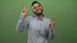 © Krakenimages.com - Man smiling and flashing peace signs with both hands while wearing a striped shirt in a green studio; joy.