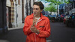 © Krakenimages.com - Man in orange jumpsuit adjusts handcuffs while making a shushing finger to lips gesture on a city street; playful defiance.