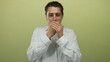 © Krakenimages.com - Young man covering mouth with hands over isolated yellow background wearing white shirt showing surprise and curiosity
