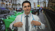 © Krakenimages.com - Young hispanic male doctor wearing a white coat and stethoscope stands confidently on a busy city street.