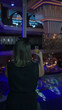 © Krakenimages.com - Woman drinking from a glass at an indoor bar balcony under blue purple club lighting; evening calm now.