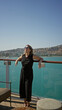 © Krakenimages.com - Woman leaning on ship rail smiling and holding sunglasses on building deck with sea view; vacation joy.