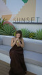 © Krakenimages.com - Woman sipping iced tea through straw while holding glass on a building terrace with succulents and sign reading sunset; serenity.