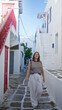 © Krakenimages.com - Woman walking with hand to hair and striped top on whitewashed steps in a narrow mykonos street; vacation leisure serenity.