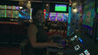 © Krakenimages.com - Young hispanic brunette woman seated at a row of slot machines playing a machine with hands on controls and smiling inside a casino building; night leisure excitement.