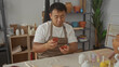 © Krakenimages.com - Man inspects clay coaster with both hands on table in studio filled with paint jars and pottery tools; patience dedication craftsmanship focus.