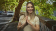 © Krakenimages.com - Young blonde woman smiling outdoors on a city street lined with trees and parked cars in the background, expressing joy and positivity in an urban environment.