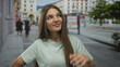 © Krakenimages.com - Girl with long brown hair stands with hand on hip and slight smile on street amid blurred pedestrians; serenity.