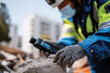 © Milos - A focused worker in safety gear uses a device while examining a disaster scene, emphasizing the urgency of rescue and recovery efforts in a chaotic environment.
