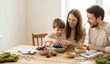 © Vika art - Happy family dyeing easter eggs with natural ingredients at wooden table.