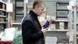 © Alexander - Shopper carefully examines product packaging in a supermarket, making a well informed buying choice. A man chooses hygiene products in a supermarket, shelves with shampoos