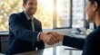 © CuteBee - A smiling businessman warmly shaking hands with a female colleague across a table in a bright, modern office, symbolizing a successful partnership, agreement, and positive professional interaction.