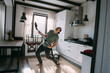 © Anna - Young happy man doing cleaning and dancing with vacuum cleaner in kitchen and living room at home.