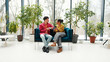 © RZ Images - Positive, confident colleagues sitting on comfortable sofa, talking, drinking coffee having break