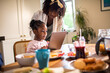 © Marko Geber - Mother helping daughter use tablet at home kitchen table