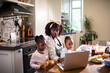 © Marko Geber - Mother working on laptop with children at breakfast in kitchen